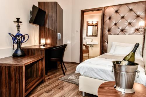 a hotel room with a bed and a desk with a bottle of wine at Simbad Hotel & Bar Superior in Mosonmagyaróvár