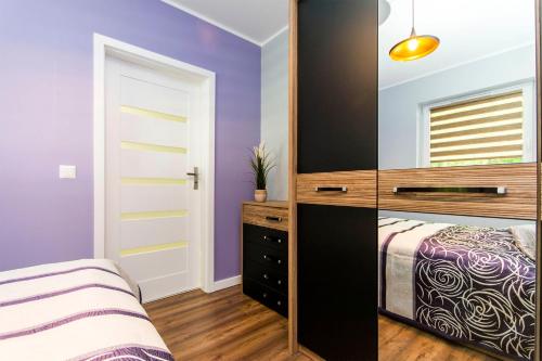 een slaapkamer met paarse muren en een bed en een spiegel bij Apartament nad morzem. Gdańsk Wyspa Sobieszewska in Gdańsk