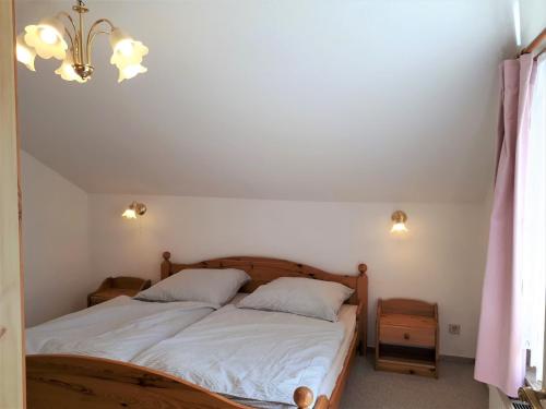 Un dormitorio con una cama con sábanas blancas y una lámpara de araña. en Sonnenblume, en Heidesee