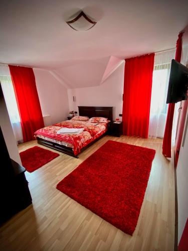 コリビツァにあるVila Simona Colibitaの赤いカーテンと赤いラグのベッドが備わるベッドルーム1室