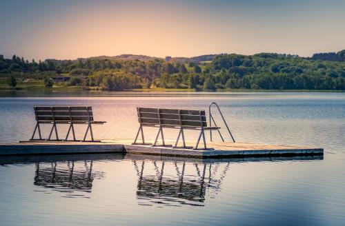 two benches sitting on a dock in a lake at Danhostel Skanderborg in Skanderborg