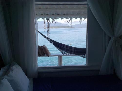 a window with a hammock looking out at the water at Cabana do Mar in Angra dos Reis