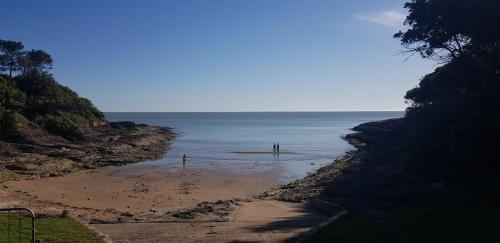 a beach with two people standing in the water at Hôtel Le Sens in Vaux-sur-Mer