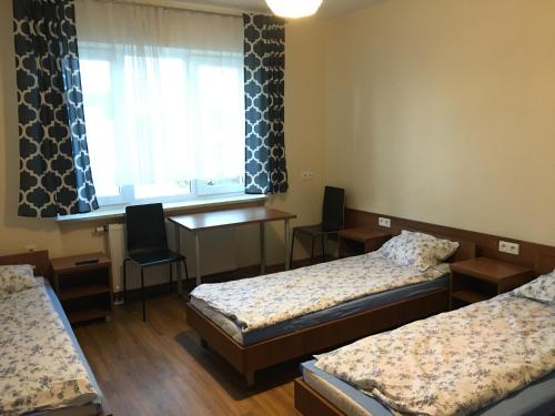 a room with two beds and a desk and a window at ANNA NOCLEGI in Raszyn