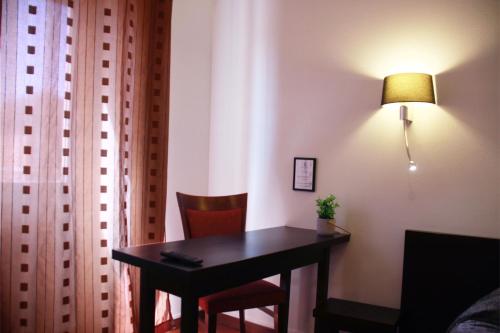 a room with a table and a lamp and a chair at L'EMBLEME - BOUTIQUE HOTEL in Beaurepaire