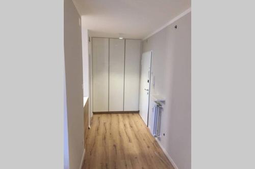 un couloir vide avec des murs blancs et du parquet dans l'établissement Apartment Mathilda, à Bolzano