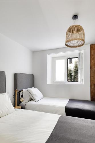 a bedroom with two beds and a window at Bem Lembrados Apartment in Cascais