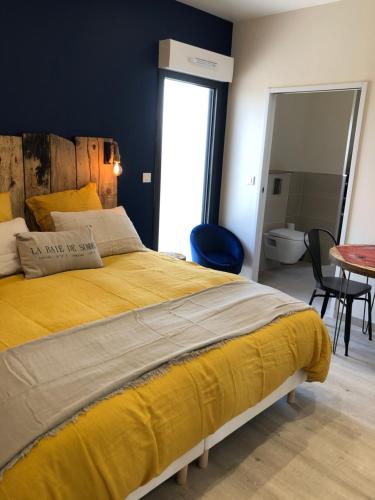 - une chambre avec un grand lit jaune et une table dans l'établissement Escale beauté le Crotoy, au Crotoy