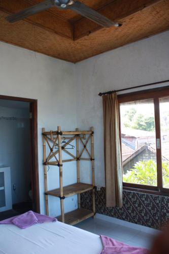 a bedroom with a book shelf and a bed and a window at Sony Home Stay in Amed