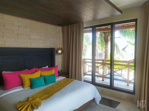 een slaapkamer met een groot bed met kleurrijke kussens bij Hotel Beló Isla Mujeres - All Inclusive in Isla Mujeres