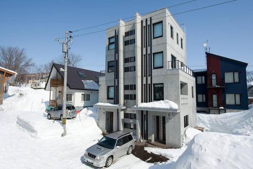 a car parked in front of a building in the snow at Udelka B in Kutchan
