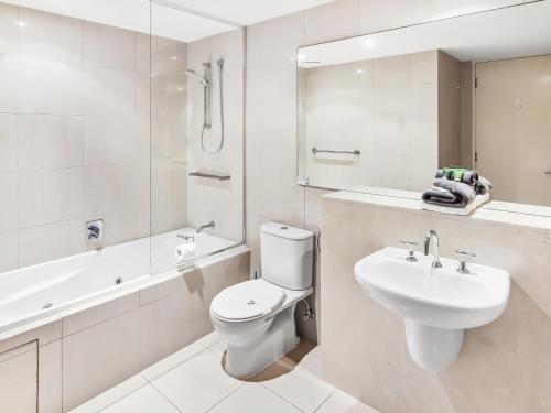 a bathroom with a sink and a toilet and a bath tub at Space Holiday Apartments in Maroochydore
