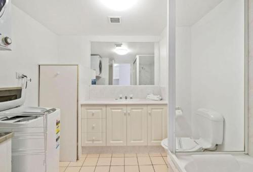 a white bathroom with a sink and a toilet at Sea Mist Palms in Gold Coast