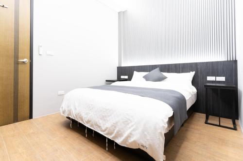 a bedroom with a large bed with white sheets at L-House時尚包棟會館 in Luodong