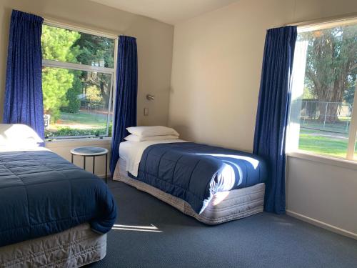 a bedroom with two beds and a window with blue curtains at Spires Barn Lodge in Christchurch