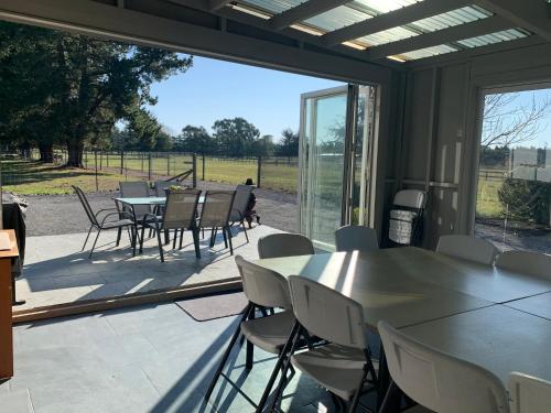 a patio with tables and chairs and a large glass window at Spires Barn Lodge in Christchurch