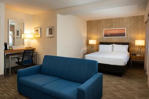a hotel room with a bed and a blue couch at Holiday Inn Express San Francisco Airport South, an IHG Hotel in Burlingame