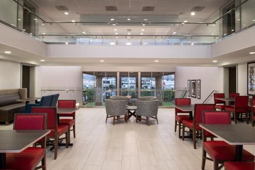 a dining room with tables and chairs and windows at Holiday Inn Express San Francisco Airport South by IHG in Burlingame