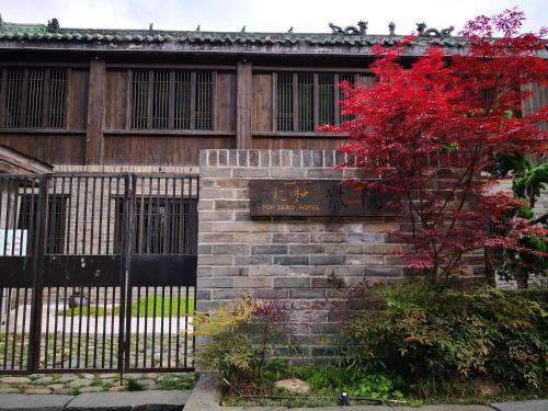 a fence in front of a building with a red tree at 武当山太和紫隐酒店 in Wudangshan