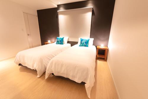 een slaapkamer met 2 bedden en blauwe kussens bij Firefly Apartments in Hakuba