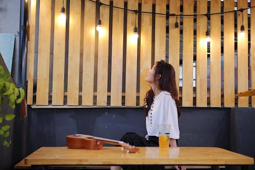 a woman sitting on a bench at a table at The Autumn Homestel in Hanoi