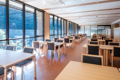 a dining room with tables and chairs and large windows at Izumo Yumuraonsen Seiranso in Unnan