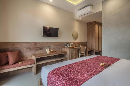 a bedroom with a bed and a tv on the wall at Merak Village by Prasi in Ubud