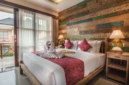 a bedroom with a large bed and a window at Merak Village by Prasi in Ubud