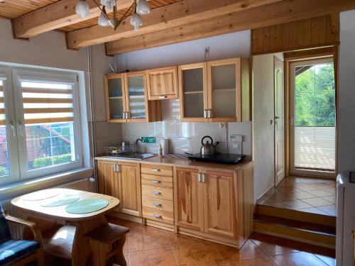 a kitchen with wooden cabinets and a small table at Apartament Suzyw Kicek in Sucha Beskidzka