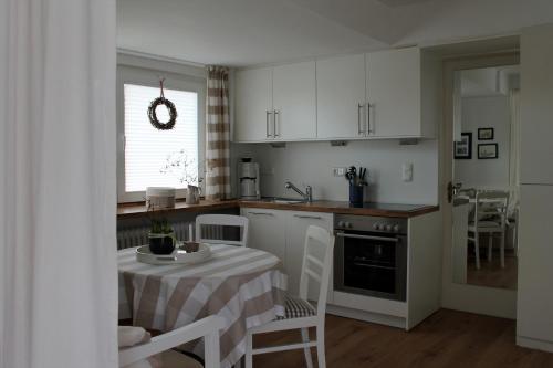 uma cozinha com uma mesa e uma cozinha com armários brancos em Seeblick em Westensee