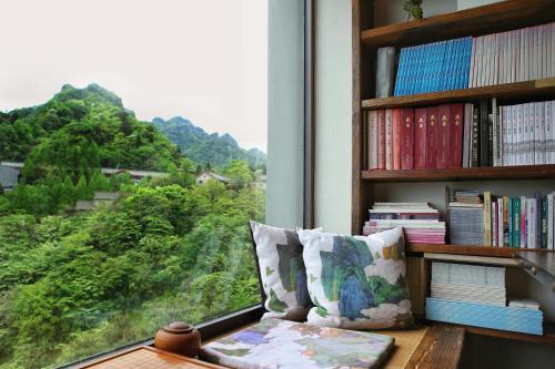 a room with a window with a book shelf and a pillow at 武当山太和紫隐酒店 in Wudangshan