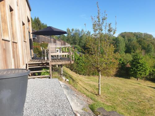 a house with a porch with an umbrella and a trash can at Chalet Bonne Humeur in Houffalize