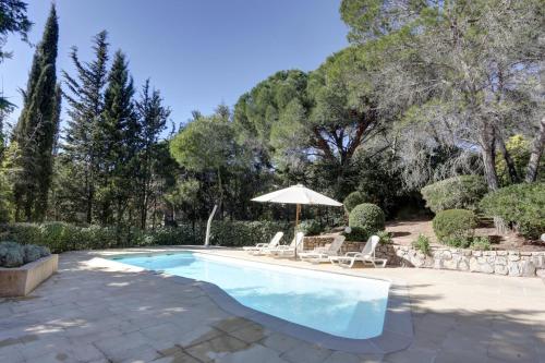 une piscine avec deux chaises et un parasol dans l'établissement villa 8 pers, climatisée, piscine chauffée, un havre de paix sous les pins parasols, à Roquebrune-sur Argens