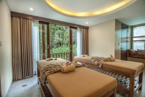 a room with two beds and a balcony at Merak Village by Prasi in Ubud