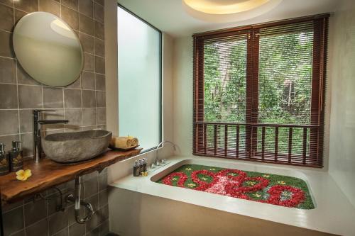 uma casa de banho com uma banheira cheia de flores em Merak Village by Prasi em Ubud
