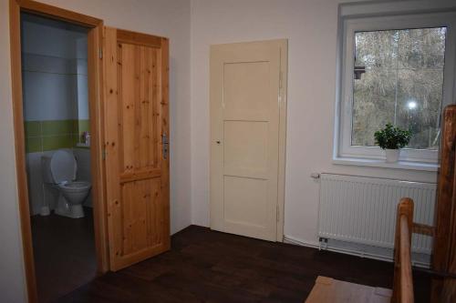 a bathroom with a toilet and a door and a window at Chalupa Měděnecká in Kovářská