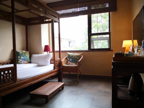 a bedroom with a canopy bed and a chair and a window at 武当山太和紫隐酒店 in Wudangshan