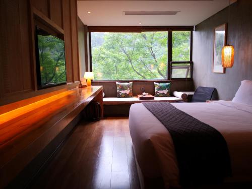 a bedroom with a bed and a couch and a window at 武当山太和紫隐酒店 in Wudangshan