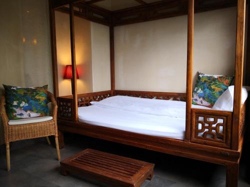 a bedroom with a canopy bed and two chairs at 武当山太和紫隐酒店 in Wudangshan