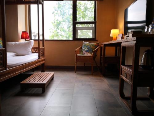 a living room with a couch and a desk and window at 武当山太和紫隐酒店 in Wudangshan