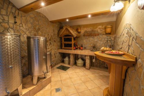 una cocina grande con una habitación con paredes de piedra, ducha y mesa en Vineyard Cottage Krivic, en Trebelno