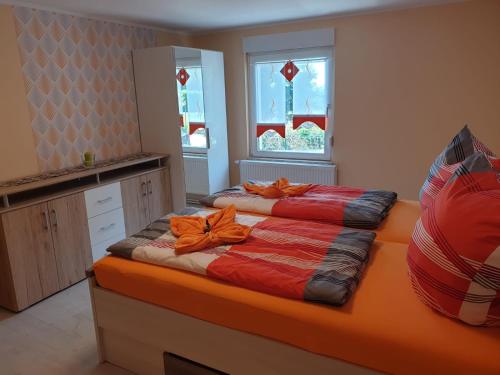 una camera con 2 letti con cuscini arancioni di Skibbi`s Ferienhaus an der Sonnenloipe a Friedrichsbrunn