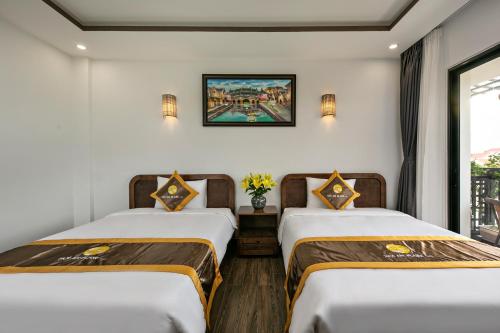 two beds in a room with a window at Villa Blake Hoi An in Hoi An