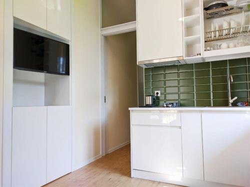 eine Küche mit weißen Schränken und einem Flachbild-TV in der Unterkunft Guest House Bolnisi - Green Apartment in Bolnisi
