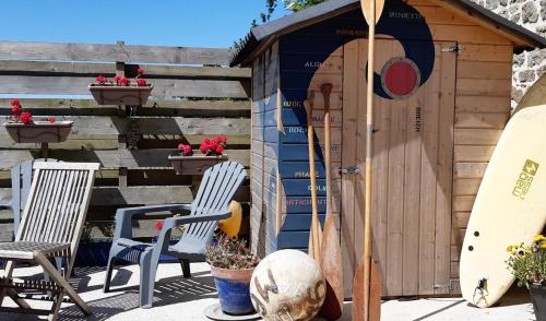 a small shed with two chairs and a surfboard at L'écurie Kerdoel in Cléder