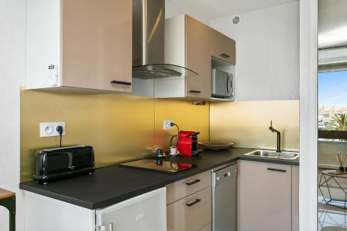 une cuisine avec des armoires blanches et un comptoir noir dans l'établissement L'After Port Nature, au Cap d'Agde