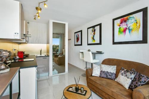 a living room with a couch and a kitchen at L'After Port Nature in Cap d'Agde