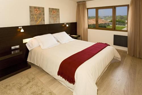 a bedroom with a large bed with a large window at Apartamentos Ciudad de Petra in Santillana del Mar