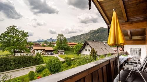 a balcony with an umbrella and a view of a village at Gästehäuser Schwemmbauer in Reit im Winkl