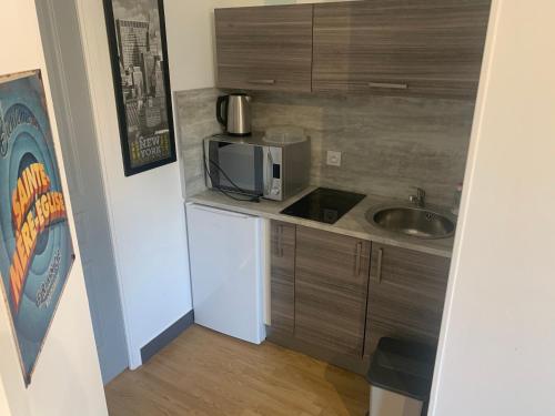une petite cuisine avec un évier et un micro-ondes dans l'établissement Gîtes de l'Eglise, à Sainte-Mère-Église